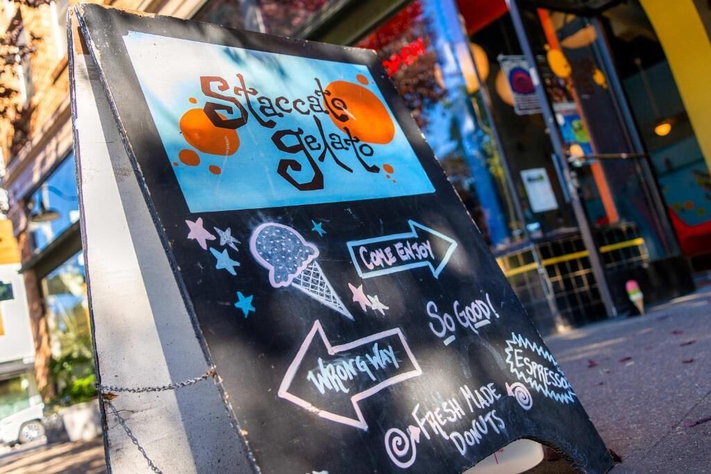 A chalkboard sign with 'Staccato Gelato' and 'Come Enjoy' written on it.