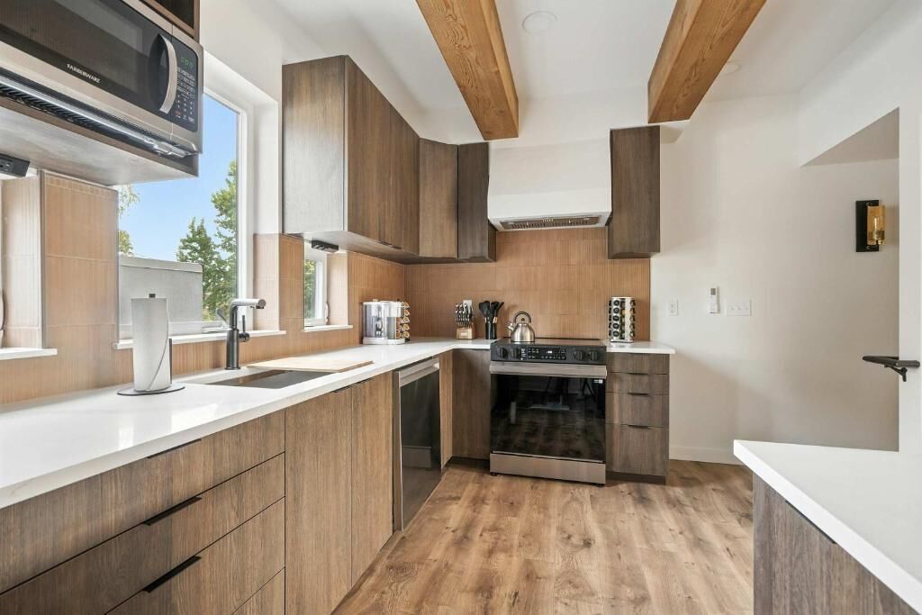 A modern kitchen with wooden cabinets, a stainless steel oven, and a microwave.