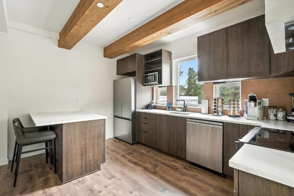 A modern kitchen with wooden cabinets, a built-in microwave, and a large window.