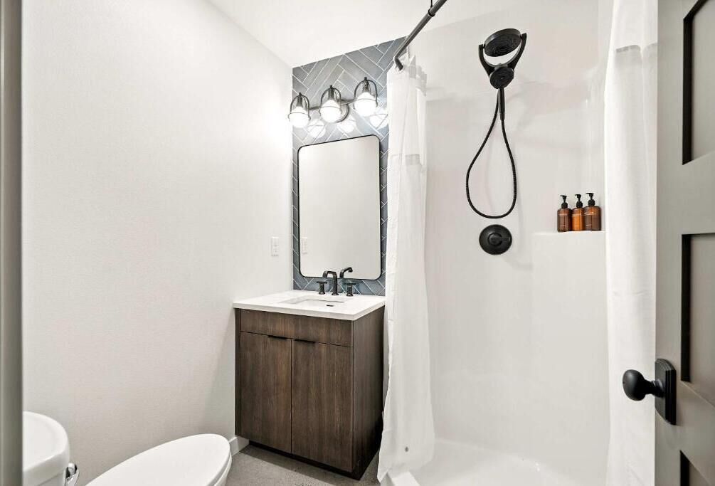A modern bathroom with a shower, toilet, and vanity.