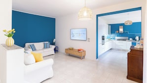 A modern living room with a white sofa, a coffee table, and a blue accent wall. - Linda Blue Bay, Sorrento Coast (Piano di Sorrento)