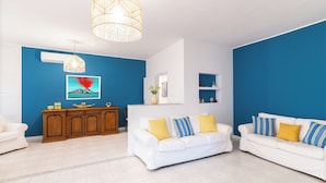 A living room with a white sofa, a wooden cabinet, and a blue accent wall. - Linda Blue Bay, Sorrento Coast (Piano di Sorrento)