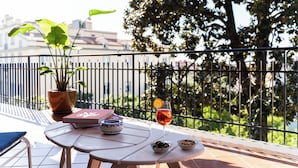 A balcony with a table, a potted plant, a book, a glass of drink, and a bowl of olives. - Linda Blue Bay, Sorrento Coast (Piano di Sorrento)