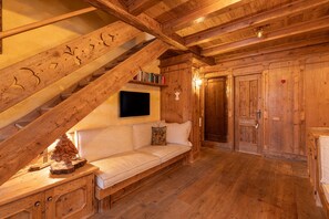 A wooden interior with a sofa, a staircase, and a door. - Casa Punta Nera 2, spacious and comfortable (Cortina d´Ampezzo)
