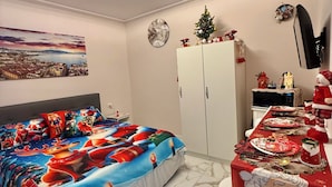 Una camera da letto con un letto, una scrivania con una sedia, un armadio, una TV e un orologio a parete.