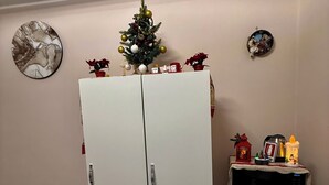 Una stanza con un armadio bianco, un piccolo frigorifero, un forno a microonde e un albero di Natale.