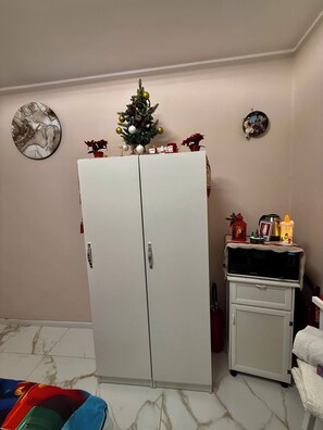 Une chambre avec une armoire blanche, un petit réfrigérateur, un four à micro-ondes et un sapin de Noël.