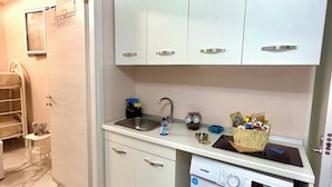 Una cucina compatta con lavatrice, lavello e pensili.