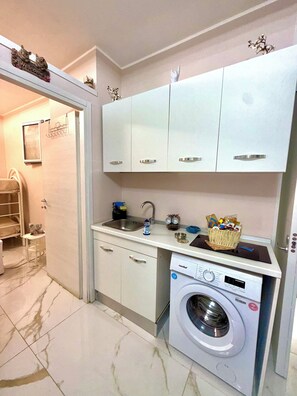 A compact kitchen with a washing machine, a sink, and cabinets. - House in the ancient heart (Napoli)
