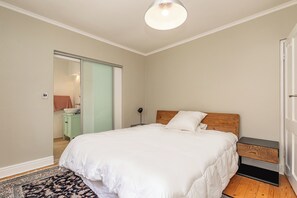 Une chambre à coucher avec un lit, une table de chevet, une commode et un miroir.