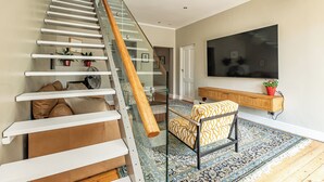A modern staircase with glass railings, a wooden handrail, and a patterned rug. - 3-bedroom house with mountain views, pool and fireplaces in Cape Town. (Cape Town)