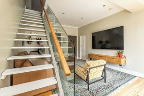 Un escalier moderne avec des rampes en verre, une main courante en bois et un tapis à motifs.