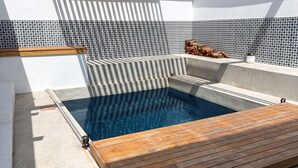 A modern outdoor pool area with a wooden deck, a built-in seating area, and a tiled wall. - 3-bedroom house with mountain views, pool and fireplaces in Cape Town. (Cape Town)