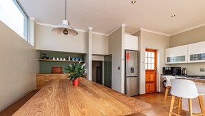 A modern kitchen with a wooden island, stainless steel appliances, and a large window. - 3-bedroom house with mountain views, pool and fireplaces in Cape Town. (Cape Town)