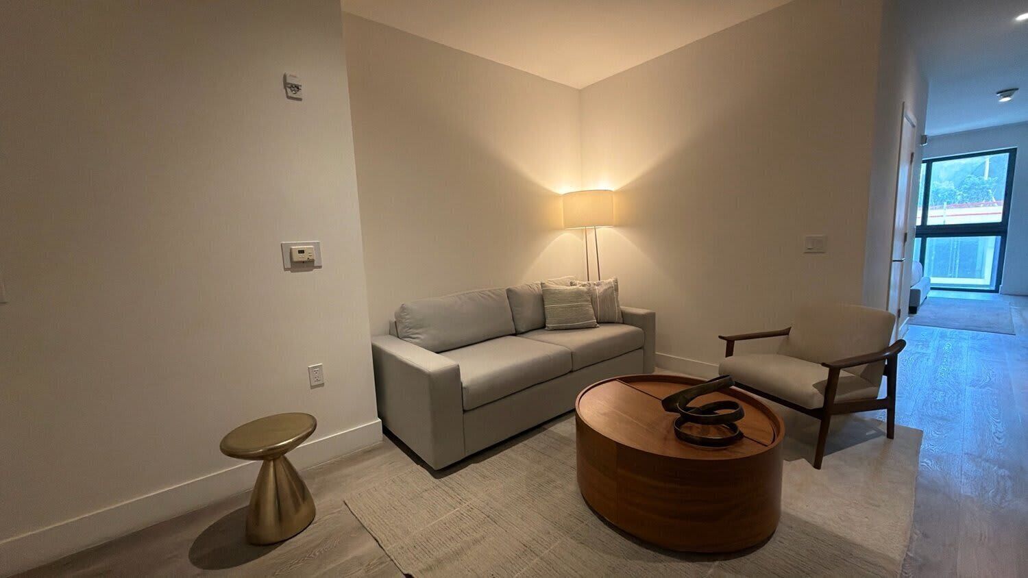 A modern living room with a sofa, armchair, round coffee table, and a floor lamp.