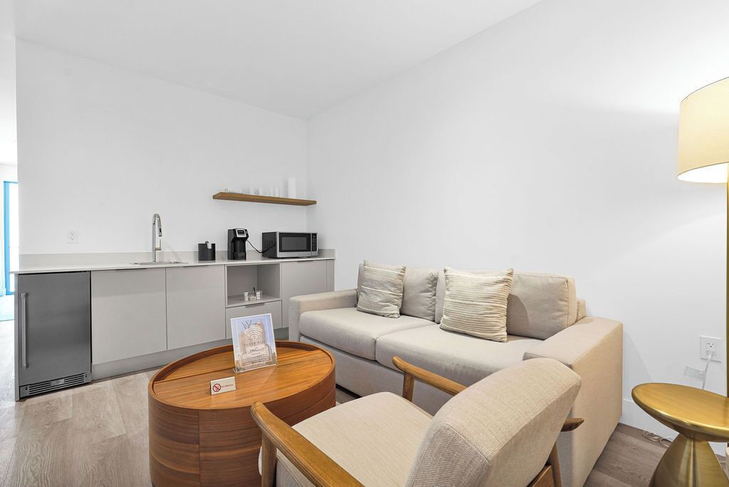 A modern living room with a sofa, a coffee table, a microwave, and a small kitchen area.