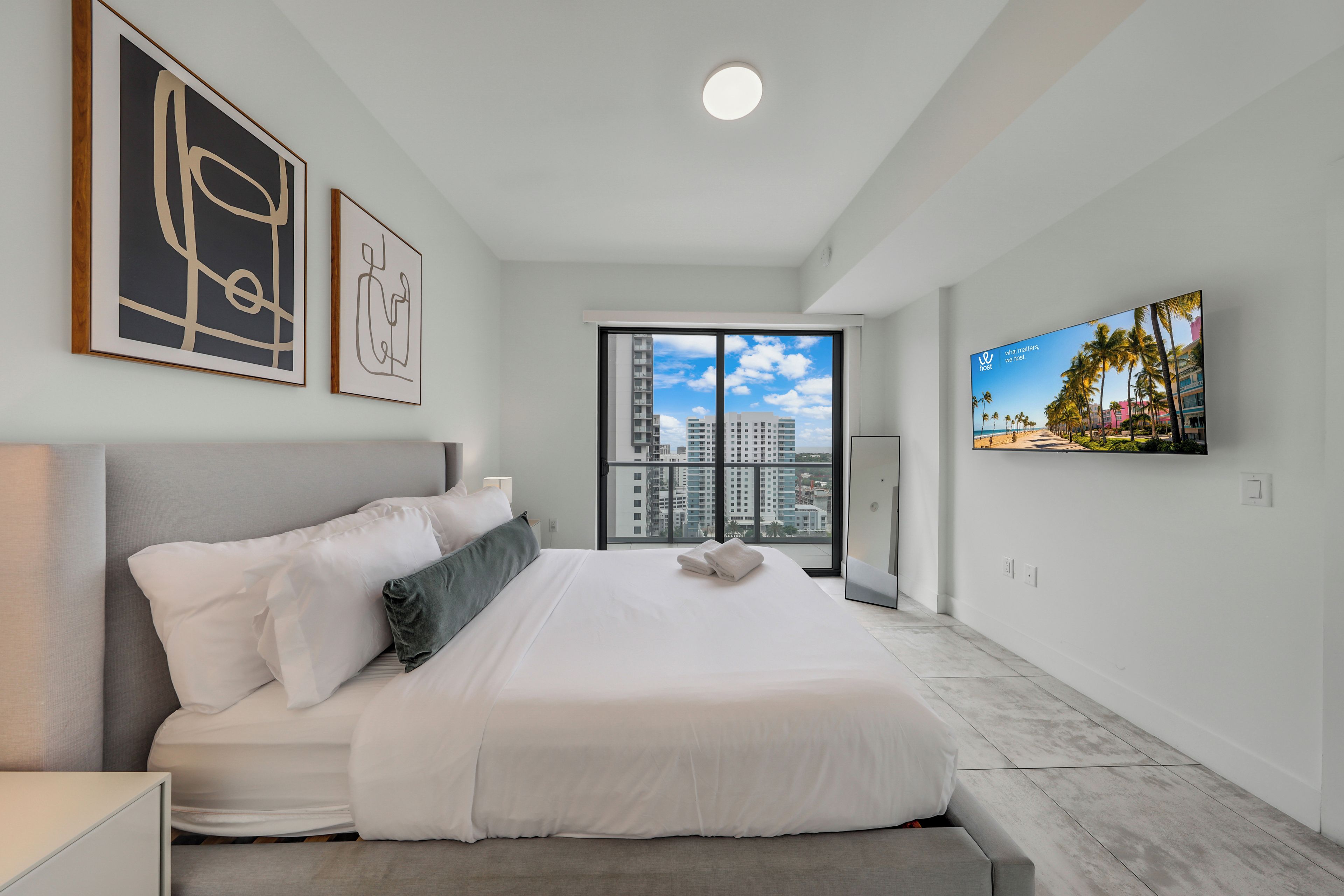 Ein modernes Hotelzimmer mit einem großen Bett, einem Flachbildfernseher und einem Balkon mit Blick auf die Stadt.