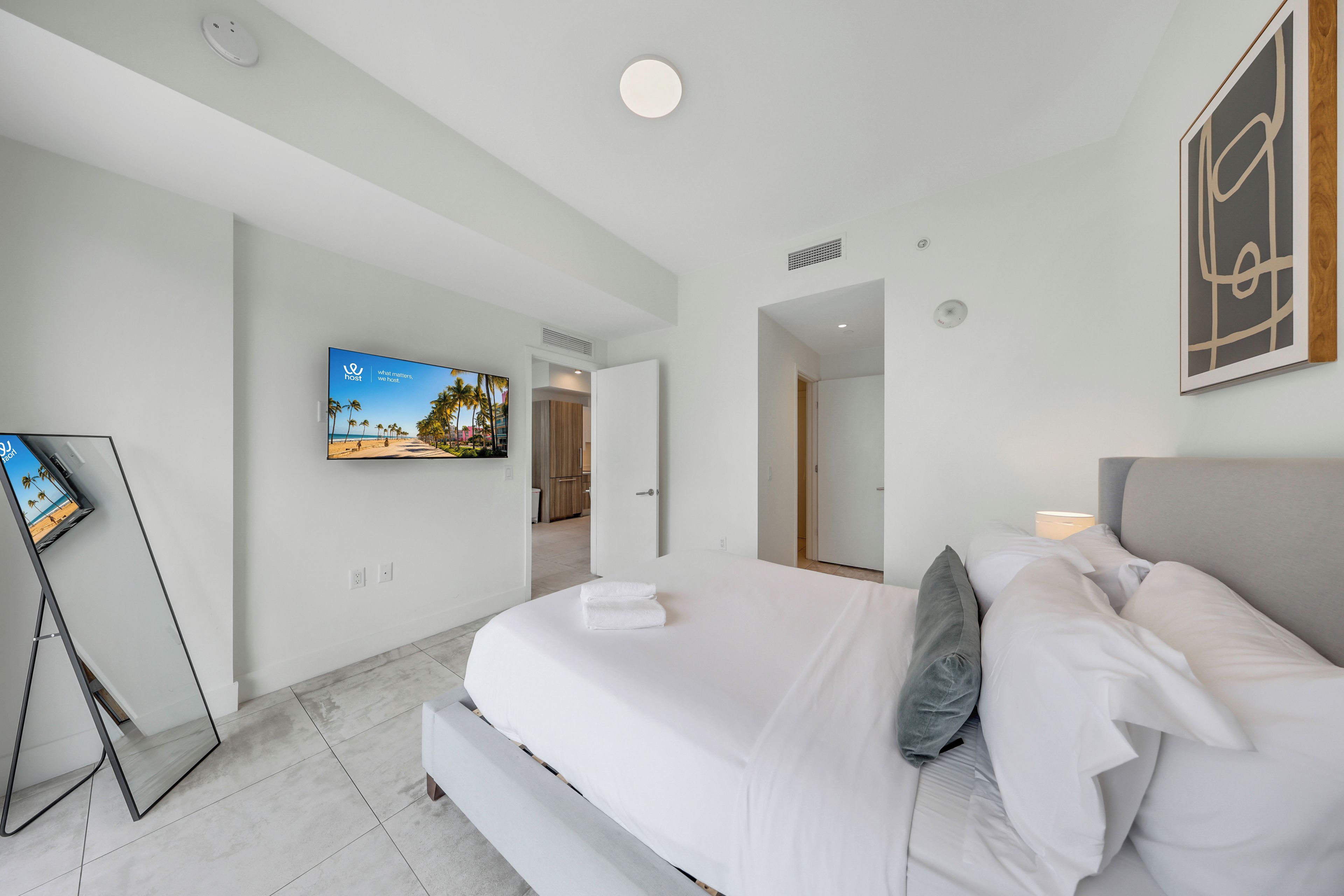 Ein modernes Hotelzimmer mit einem großen Bett, einem an der Wand befestigten Flachbildfernseher und Meerblick durch das Fenster.