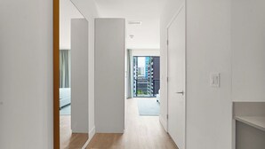 A hallway with white walls and wooden flooring leading to a balcony with a view of buildings. - Brickell Building City Centre - We Host (Miami)