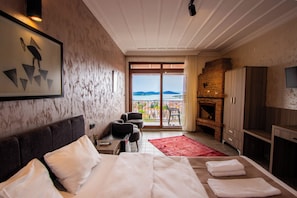 Ein Hotelzimmer mit Bett, Schreibtisch, Stuhl, Fernseher, Kamin und Blick ins Freie.
