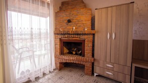 Una habitación con chimenea de ladrillo, un armario de madera y una mesa con sillas.