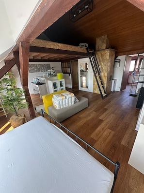 A loft-style room with exposed wooden beams, a staircase, a kitchenette, and a dining area. - Top floor apartment near the old town & Nuremberg trade fair (Nürnberg)