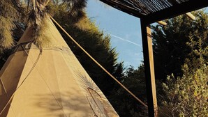 Ein Zelt auf einer Holzterrasse, überdacht mit einer Metallkonstruktion.