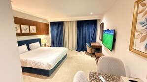 A hotel room with a bed, a desk, a chair, a television, and a framed picture on the wall. - Apartment beside Airport, City stars Nasr City with AC (Cairo Governorate)