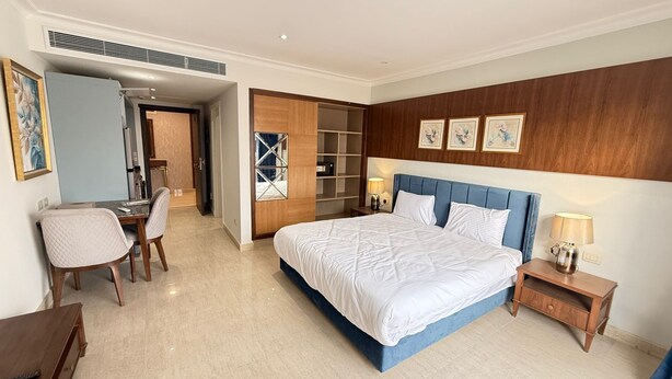 A hotel room with a large bed, a desk, and a chair. - Apartment beside Airport, City stars Nasr City with AC (Cairo Governorate)