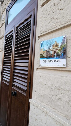 A wooden door with horizontal slats and a sign with a building image and text. - Casa Porta Nuova very close to Palazzo dei Normanni and Palermo Cathedral (Palermo)