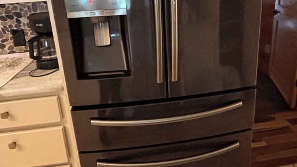 A stainless steel refrigerator with a water dispenser, a coffee maker, and a stone-patterned backsplash. - South Alabama Country Home With A Swimming Pool (Fairhope)