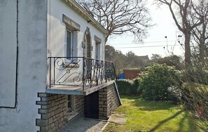 Ein Gebäude mit steinernem Sockel und weißem Oberteil, ausgestattet mit einem Balkon mit Metallgeländer und einem steinernen Bogen.