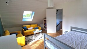 A room with a bed, a sofa, a small table, a bookshelf, and a skylight. - Renovated country house close to the ocean and hiking trails. (Névez)