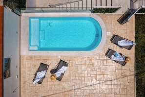 Ein Dachpool mit klar blauem Wasser, umgeben von Liegestühlen und einer gefliesten Liegefläche.