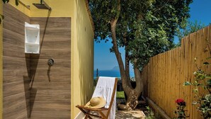Ein Wellnessbereich mit Dusche aus Holz, einem Handtuch auf einem Stuhl und Meerblick.