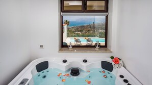 Ein Whirlpool mit Bedienfeld, ein Fenster mit Blick auf Pool und Landschaft sowie Dekoration auf der Fensterbank.