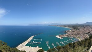 Eine Küstenstadt mit einem Jachthafen, blauem Meer und hügeliger Landschaft.