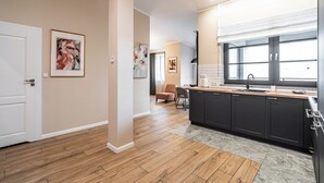 Une cuisine moderne avec des meubles de couleur sombre, une grande fenêtre et un plancher en bois.