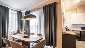 Une cuisine moderne avec un coin repas, comprenant une table ronde, des chaises et un luminaire suspendu.