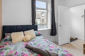 Ein Schlafzimmer mit Bett, Fenster, Tür und Blick auf ein Gebäude.