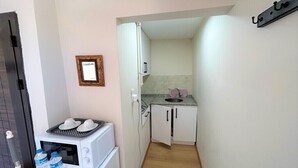 Eine kleine Küche mit Mikrowelle, Wasserflaschen, Spüle und Schränken.