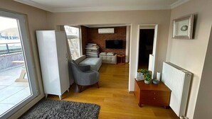 Ein modernes Wohnzimmer mit einer Couch, einem Sessel, einem Fernseher und einem Kamin.