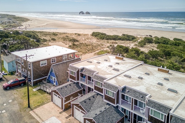 Beachfront property complex positioned steps from pristine sandy shores with dramatic offshore rock formations and rolling waves.