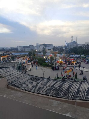 Une vaste place publique, ouverte et animée par diverses attractions, notamment un carrousel et une grande roue, le tout entouré d’immeubles.