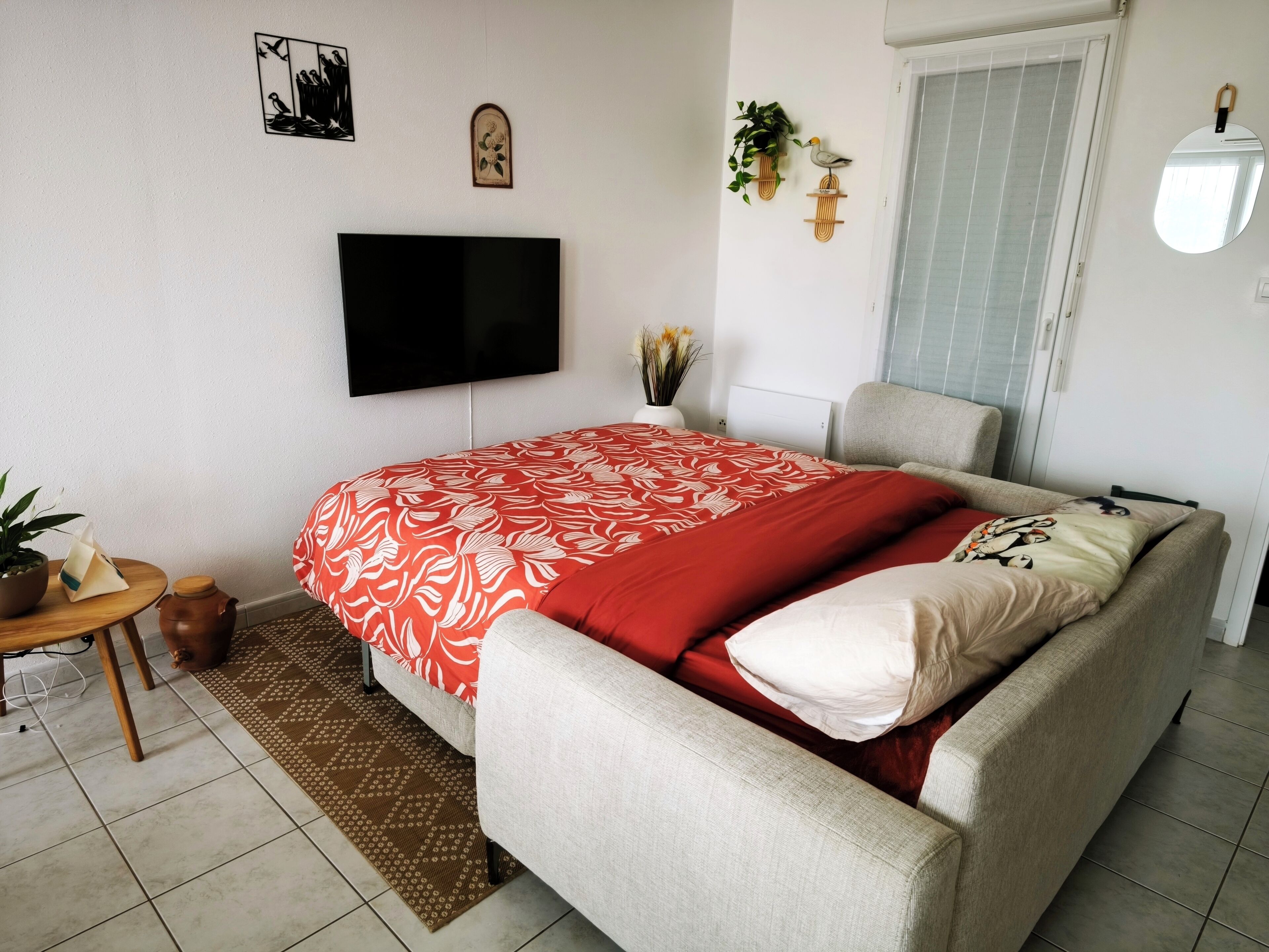 A bedroom with a bed, a TV, a window, and a door.