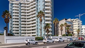 A multi-story hotel with balconies, palm trees, and a clear blue sky. - 75 Cap D'Azur (Cape Town)