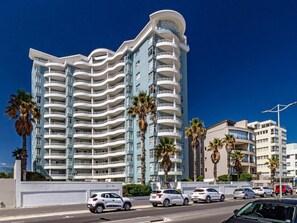 A multi-story hotel with balconies, palm trees, and a clear blue sky. - 75 Cap D'Azur (Cape Town)