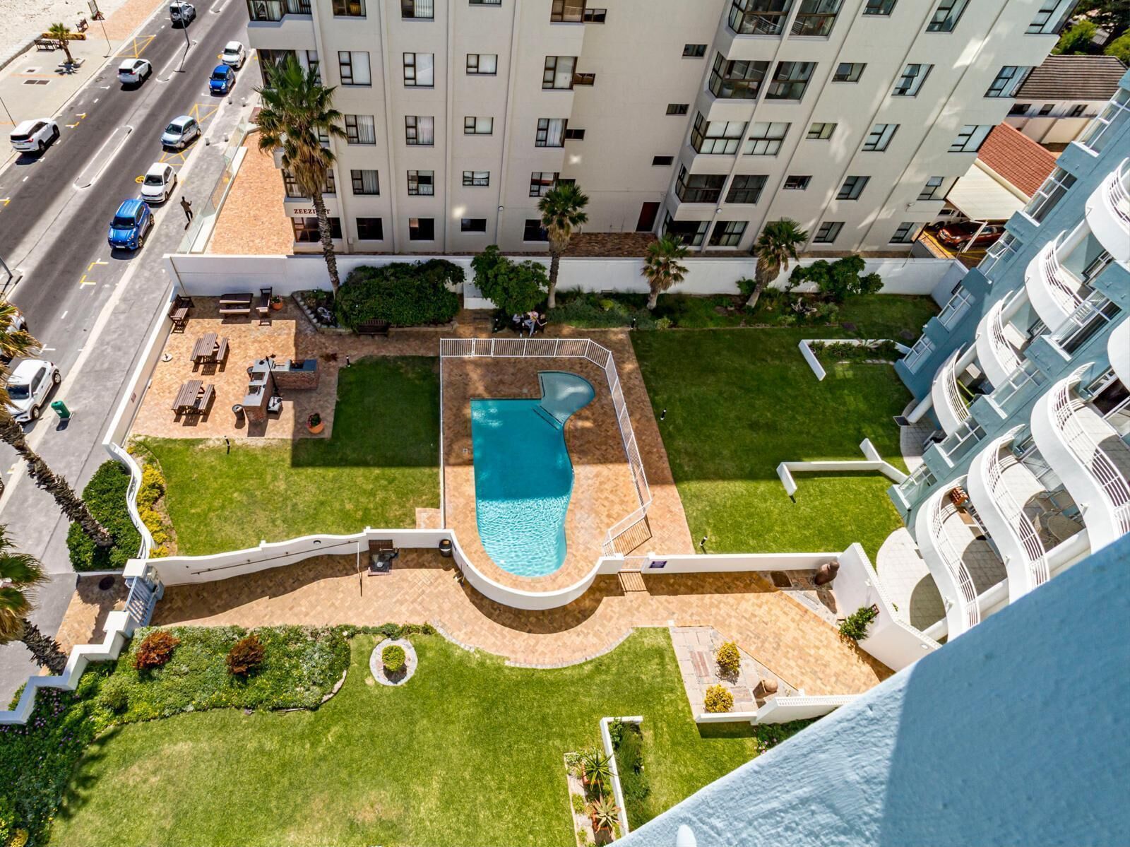 Ein Hochhaus-Hotel mit Pool auf dem Dach, mehreren Balkonen und einem gepflegten Rasen.
