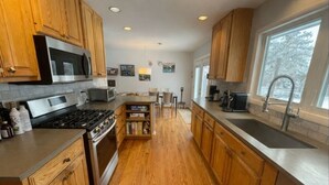 Una cocina con armarios de madera, electrodomésticos de acero inoxidable, una isla central y un ventanal grande.