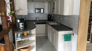 Eine kleine Küche mit weißen Schränken, einer Mikrowelle, einer Kaffeemaschine und einem Spülbecken.
